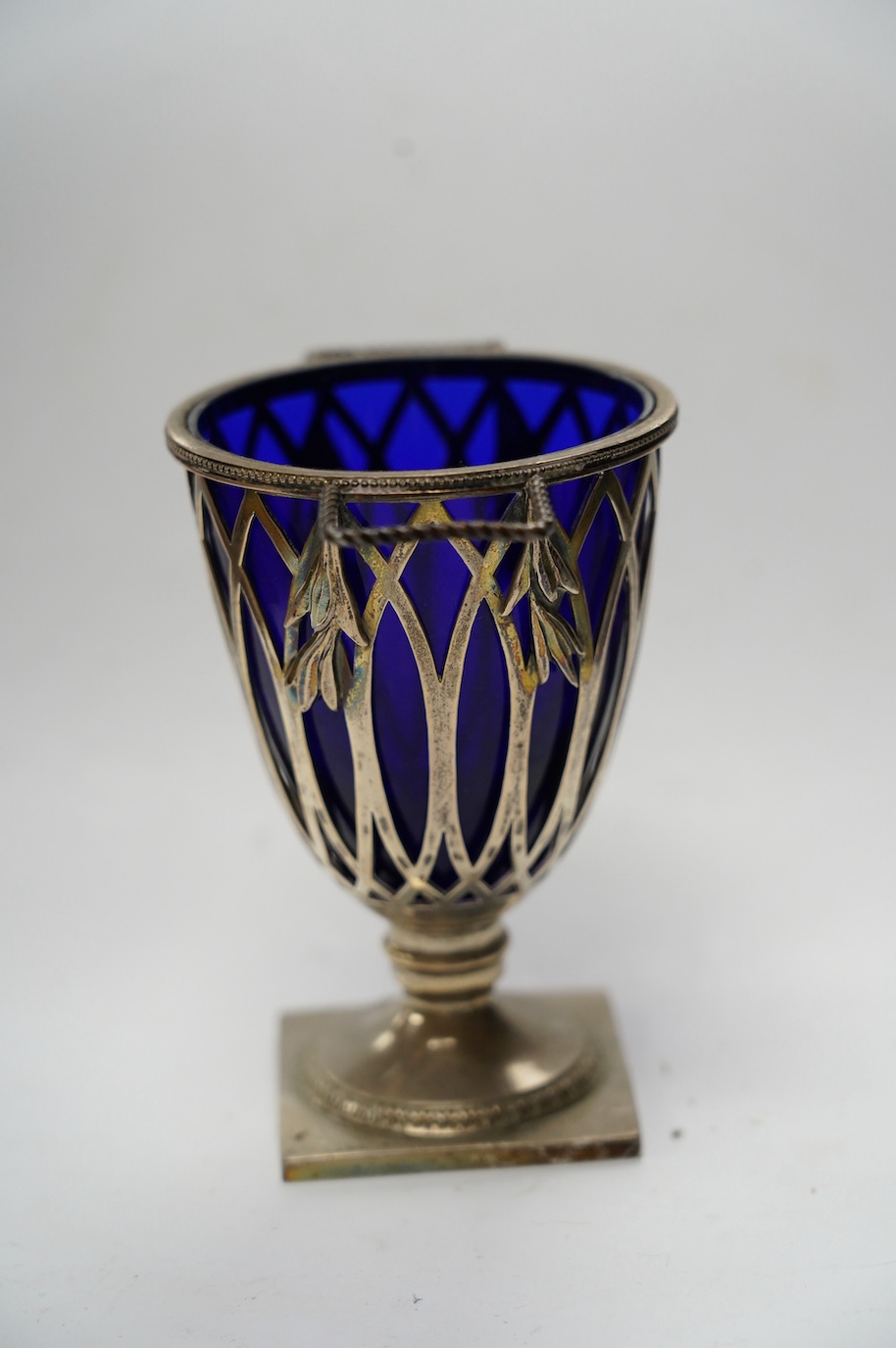 An Edwardian repousse silver porringer, Daniel & John Welby, London, 1905, height 73mm, together with a late Victorian silver two handled sugar vase with blue glass liner, London, 1895. Condition - fair